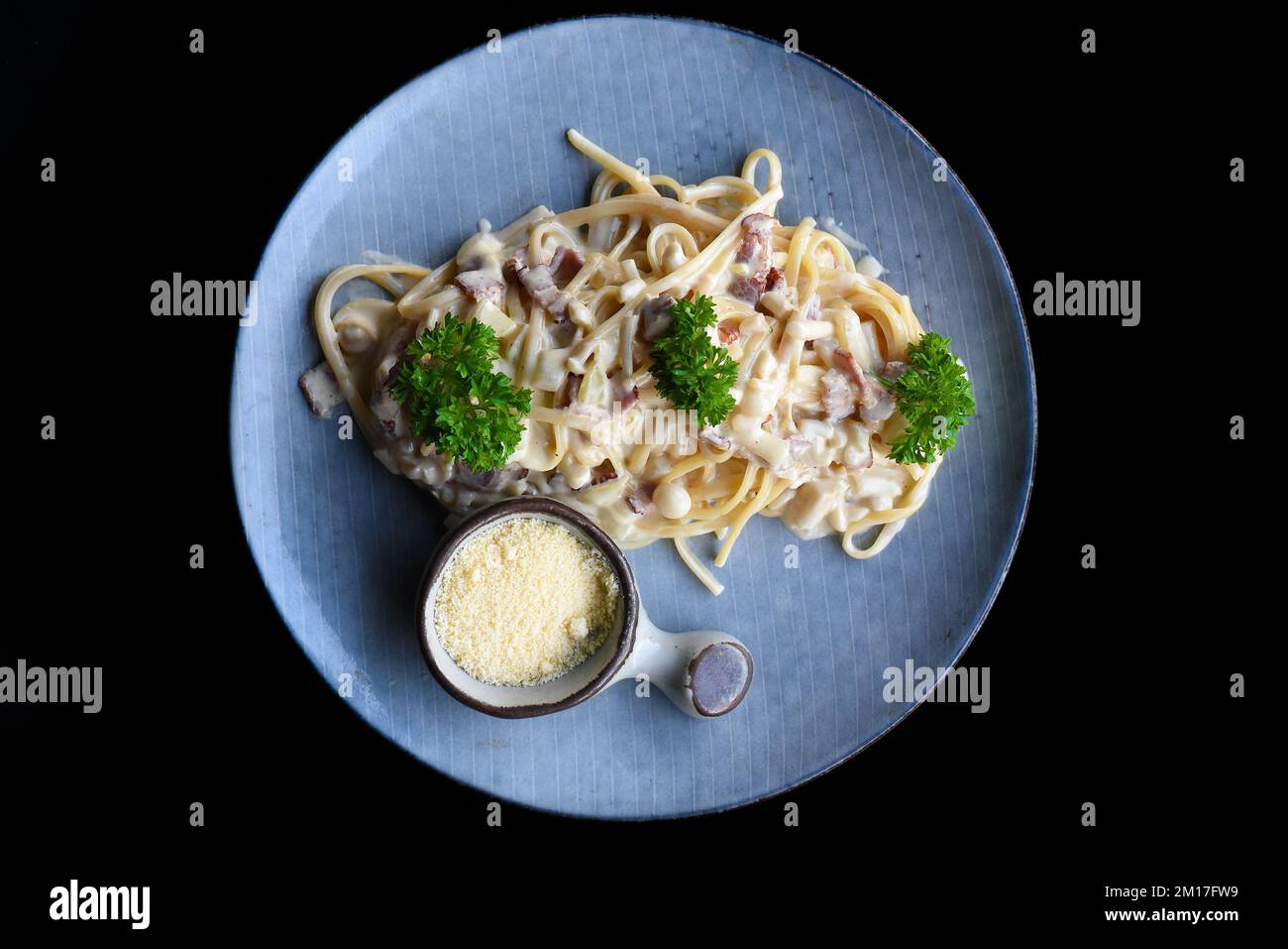 Pasta carbonara con pancetta su piatto blu isolato su sfondo nero vista dall'alto Foto Stock