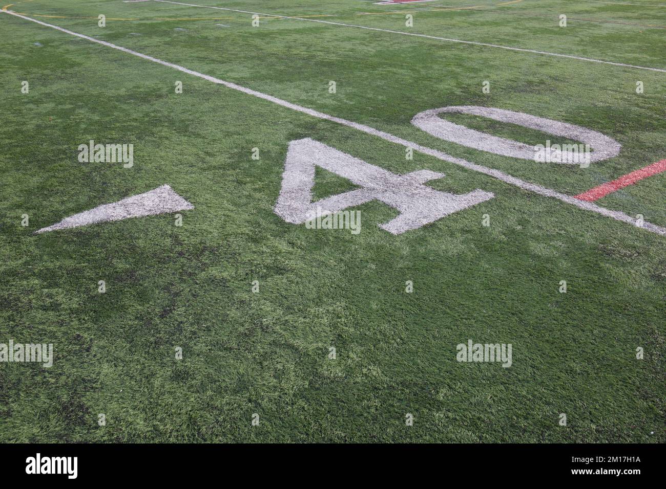 40 yard line su un campo americano di calcio di scuola superiore con numeri bianchi e verde erba sintetica e una freccia che punta a sinistra accanto al numero 4. Foto Stock