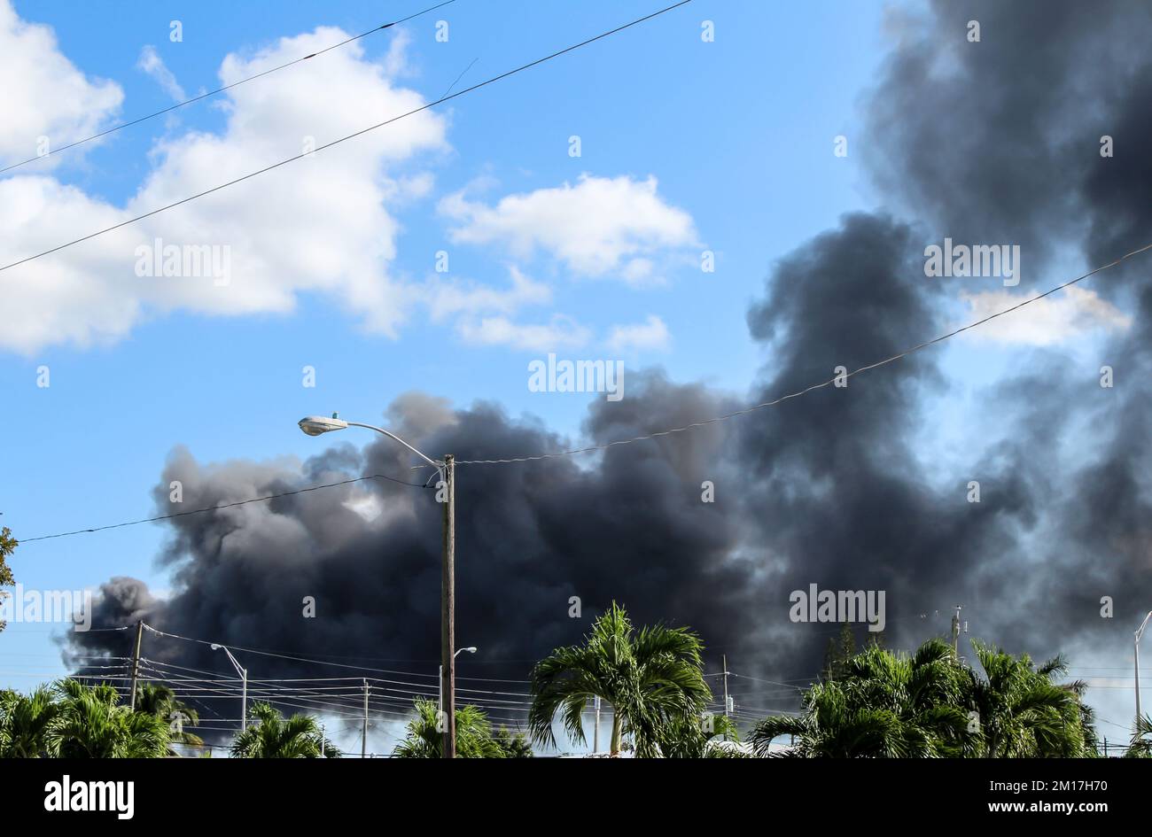 Un incendio di massa si è acceso a Hialeah, Florida, da un cantiere. Nuvole nere di fumo nel cielo. Vista da una casa residenziale a Hialeah. Foto Stock