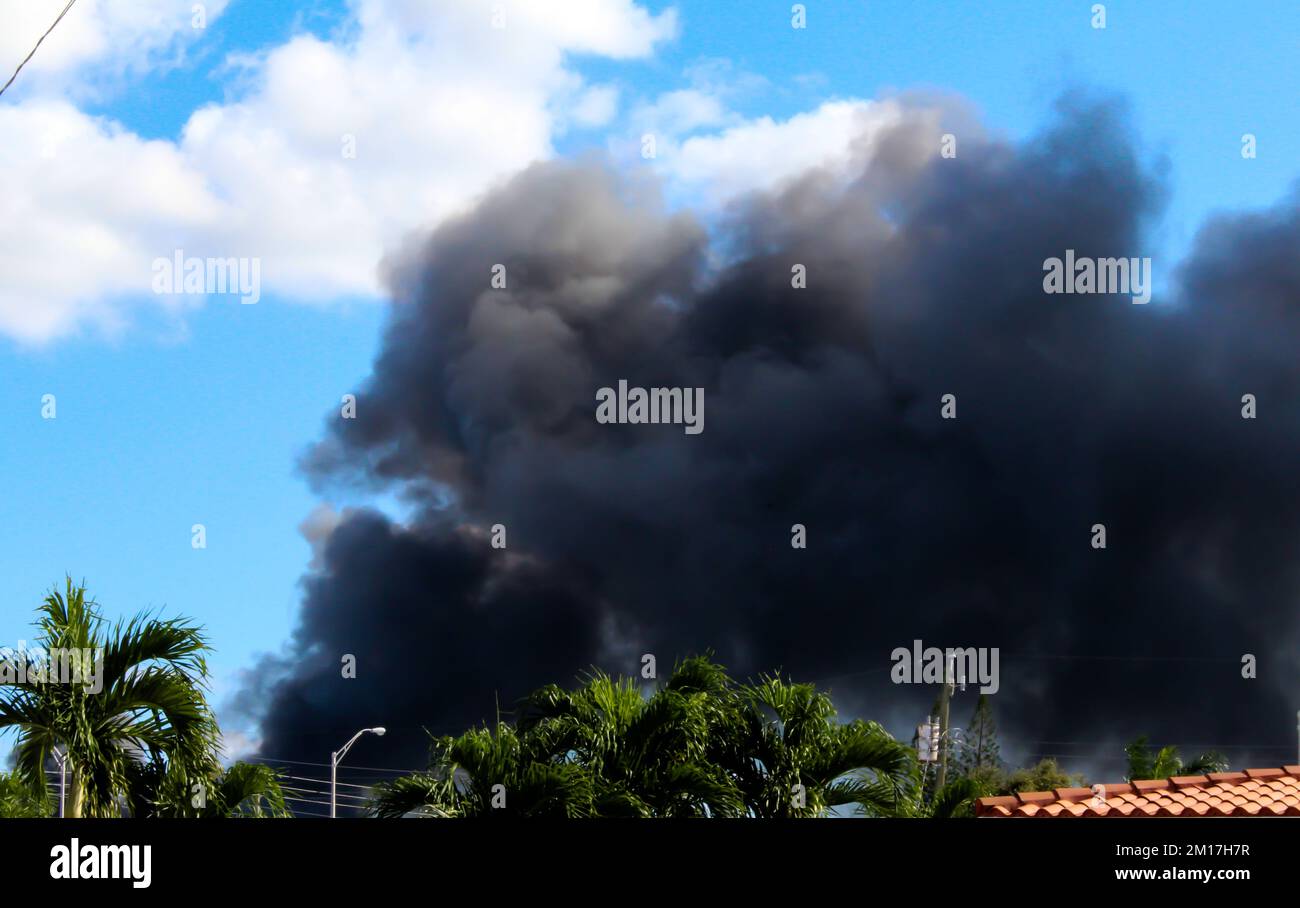 Un incendio di massa si è acceso a Hialeah, Florida, da un cantiere. Nuvole nere di fumo nel cielo. Vista da una casa residenziale a Hialeah. Foto Stock