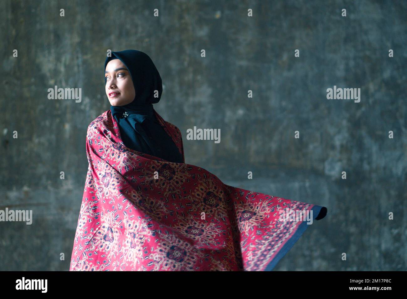 Bella donna in hijab nero con batik da Jambi, Indonesia. Foto Stock