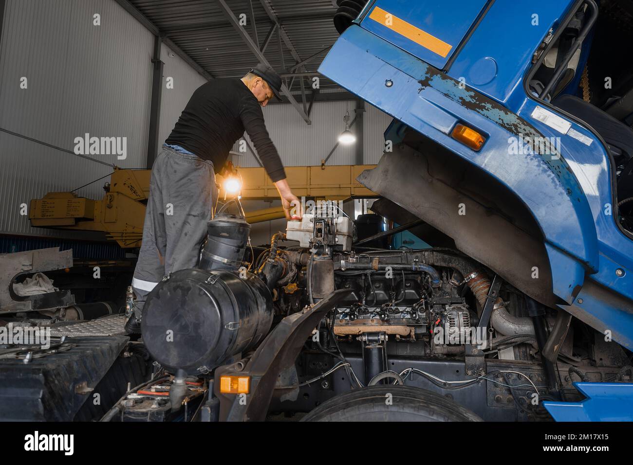 Il meccanico di automobile ripara il camion grande o il trattore in officina. Meccanico professionale ripara il motore del veicolo. Lavoratore genuino.. Foto Stock