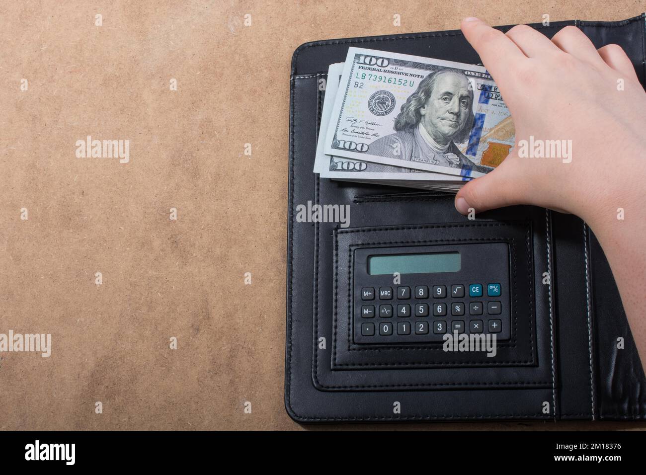 Mano che tiene le banconote del dollaro americano sulla calcolatrice Foto Stock