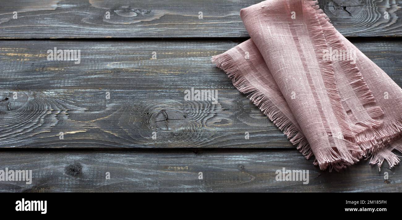 Tovagliolo di lino rosa con frangia su sfondo di legno, stile rustico, vista dall'alto, spazio Foto Stock