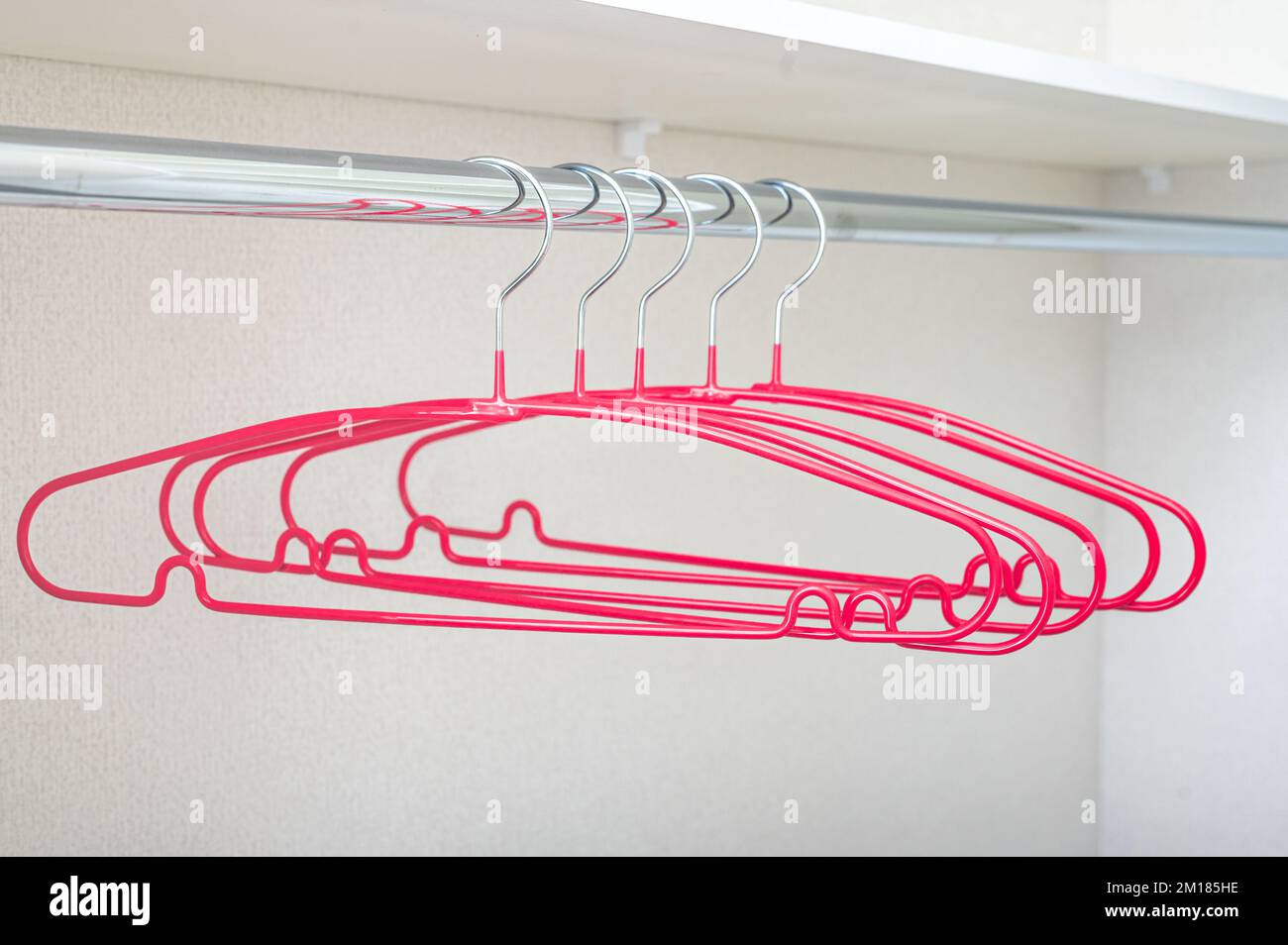 Molti appendiabiti rosa sul rack. Appendiabiti vuoto. Concetto del negozio, vendita, design, appendiabiti vuoto. Appendiabiti luminosi per cappotto e abiti su scaffale. Fila di cappotto rosa Foto Stock