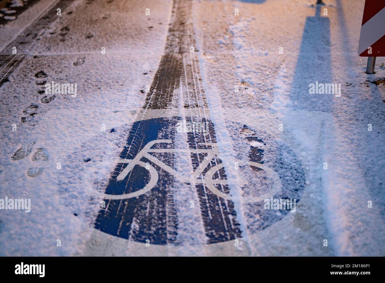 Bad Homburg, Germania. 11th Dec, 2022. Le piste per auto possono essere viste a terra nella neve appena caduta all'alba su una pista ciclabile alla periferia del centro di Bad Homburg. Credit: Frank Rumpenhorst/dpa/Alamy Live News Foto Stock