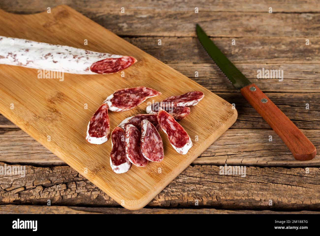 Fuet, tipica salsiccia catalana diffusa in tutta la Spagna a base di maiale e pancetta, tagliata a fette su un tagliere di legno. Foto Stock