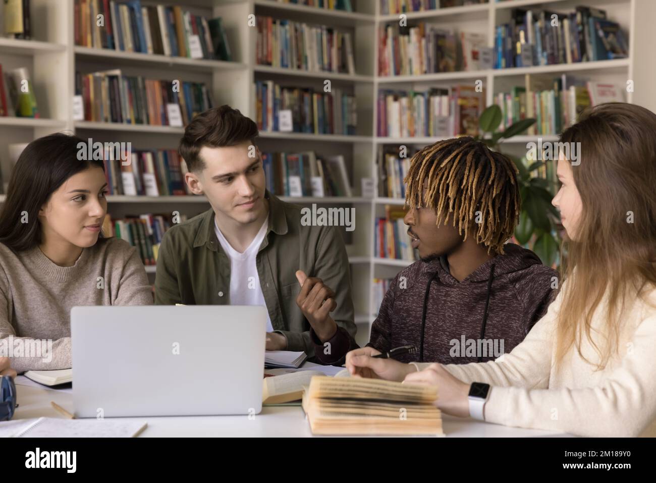 Impegnati diversi studenti impegnati a studiare in biblioteca, seduti insieme Foto Stock