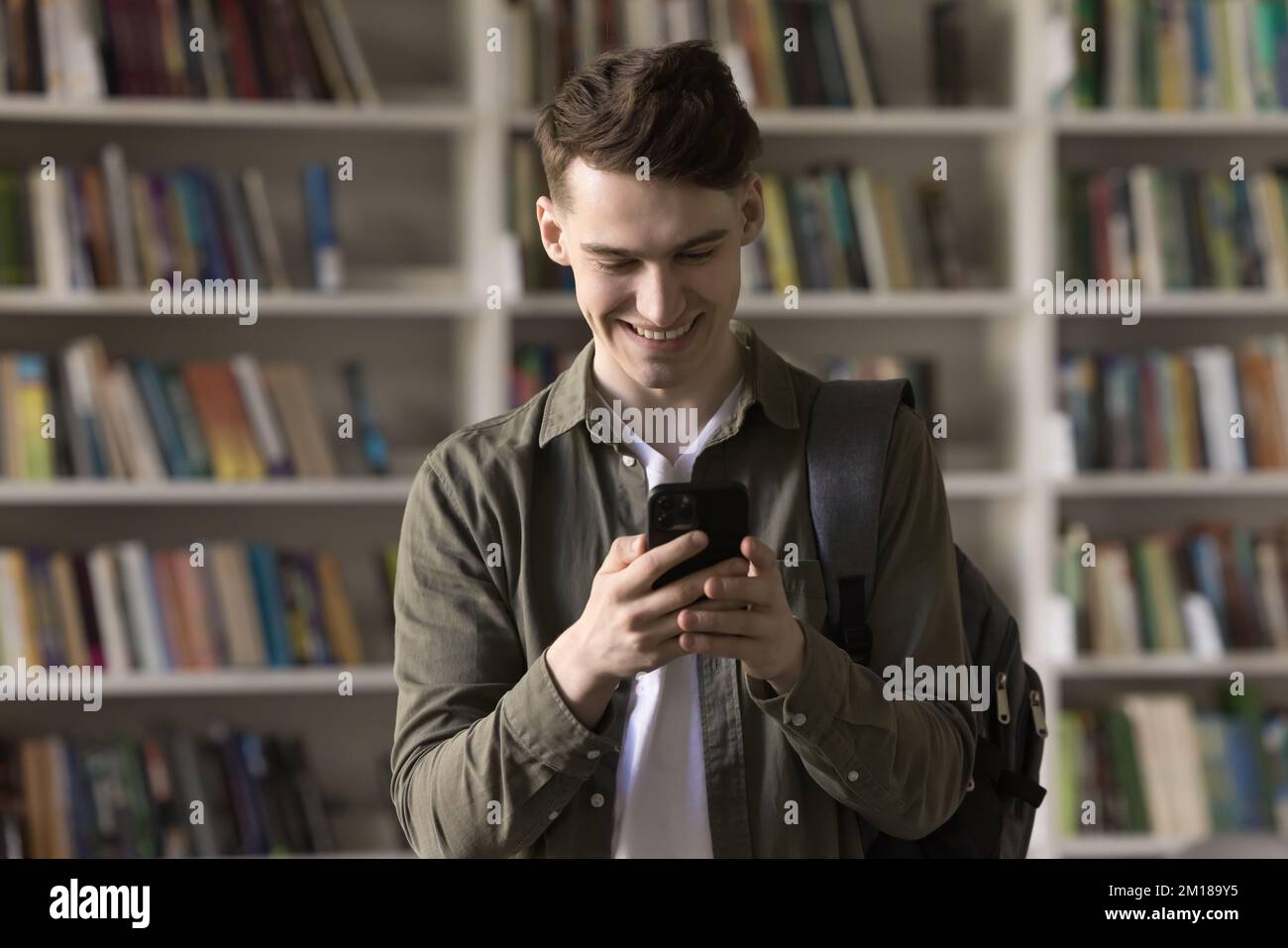 Ragazzo felice dello studente che utilizza l'applicazione di apprendimento per studiare sullo smartphone Foto Stock