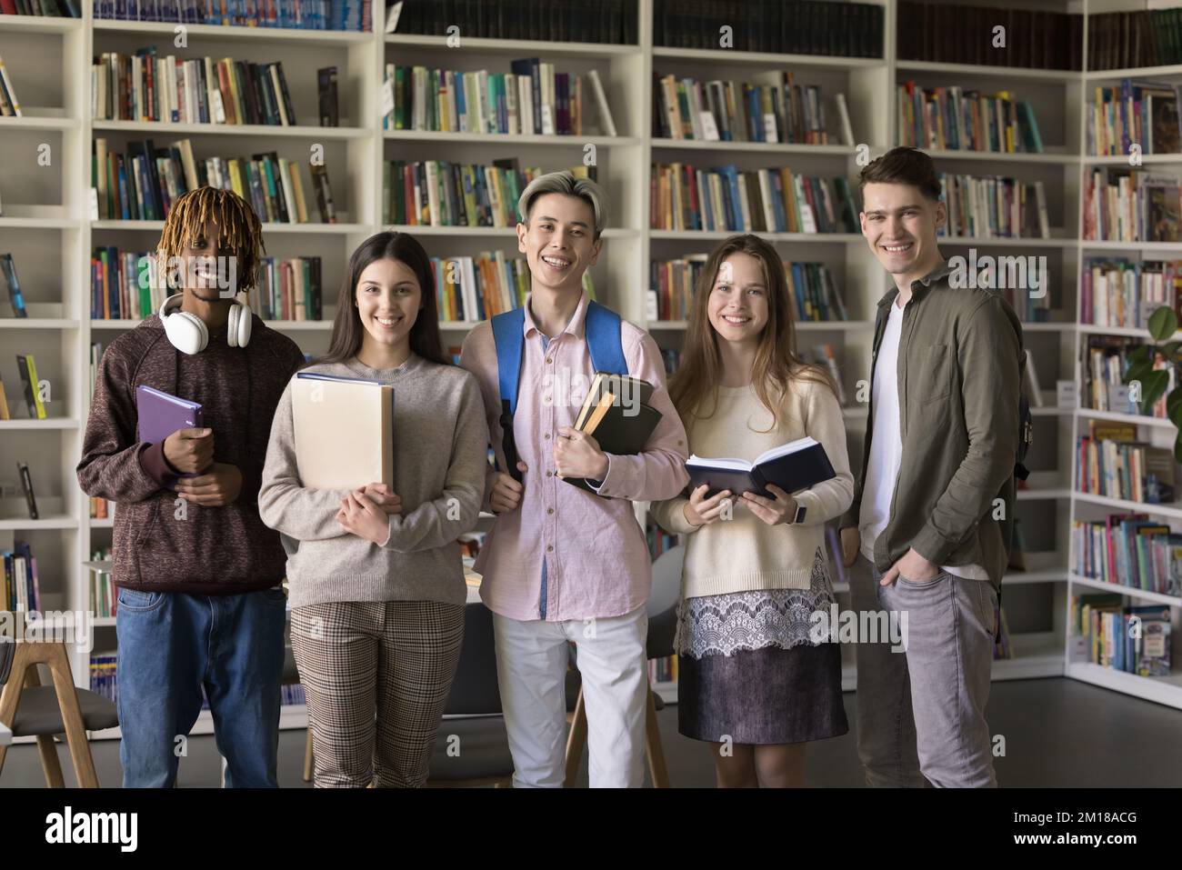 Felice diversi studenti universitari in posa per il ritratto di gruppo in biblioteca Foto Stock