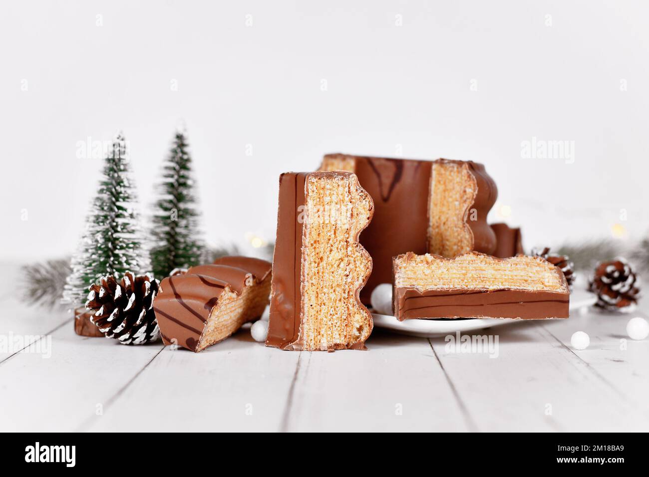 Tagliate la tradizionale torta invernale tedesca a strati chiamata 'Baumkuchen' glassata con cioccolato di fronte alla decorazione stagionale Foto Stock