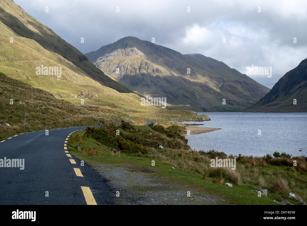 Irlanda, Doolough Valley. Luce del giorno ripresa con contrasto tra la strada gialla e le montagne. Wild Atlantic Way. Foto Stock