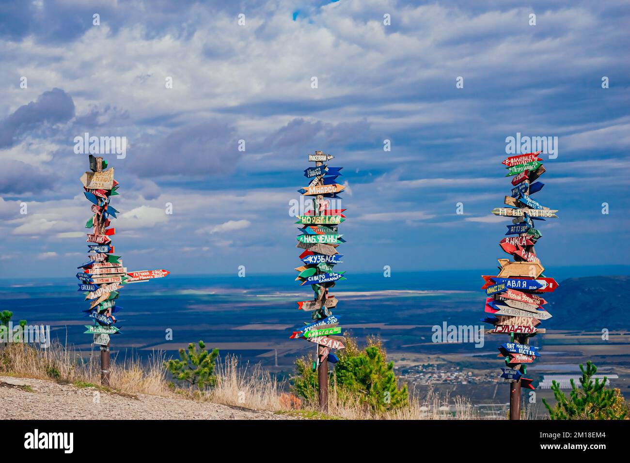 Pyatigorsk, Russia. 2022, ottobre 24. Direzione verso i diversi luoghi del mondo indicati in una segnaletica stradale. Paesaggio sul posto di montagna con città puntatori e panca di legno sulla cima Foto Stock