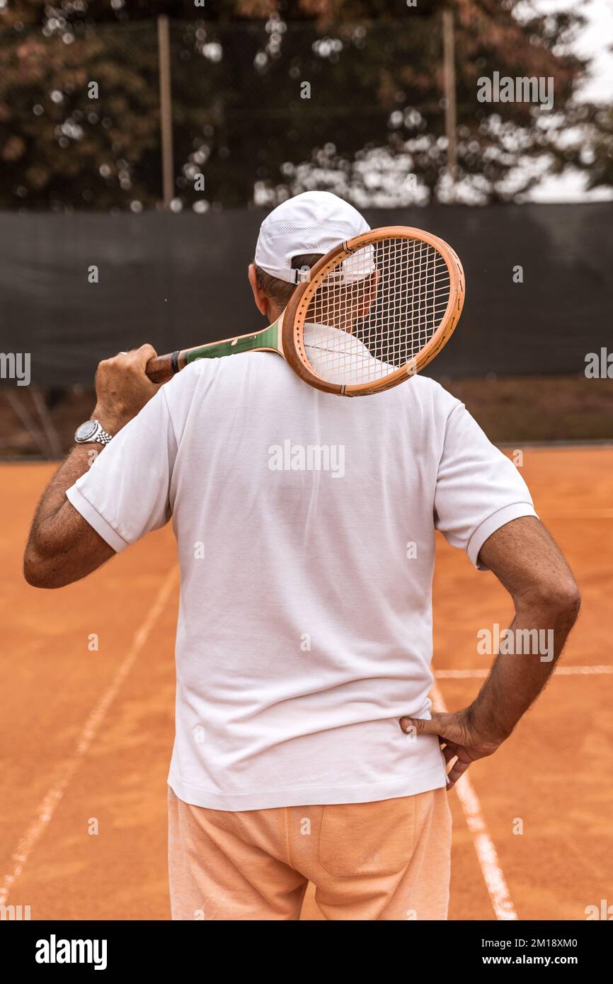 un tennista in pensione vestito di abbigliamento sportivo che posa con la  schiena alla macchina fotografica