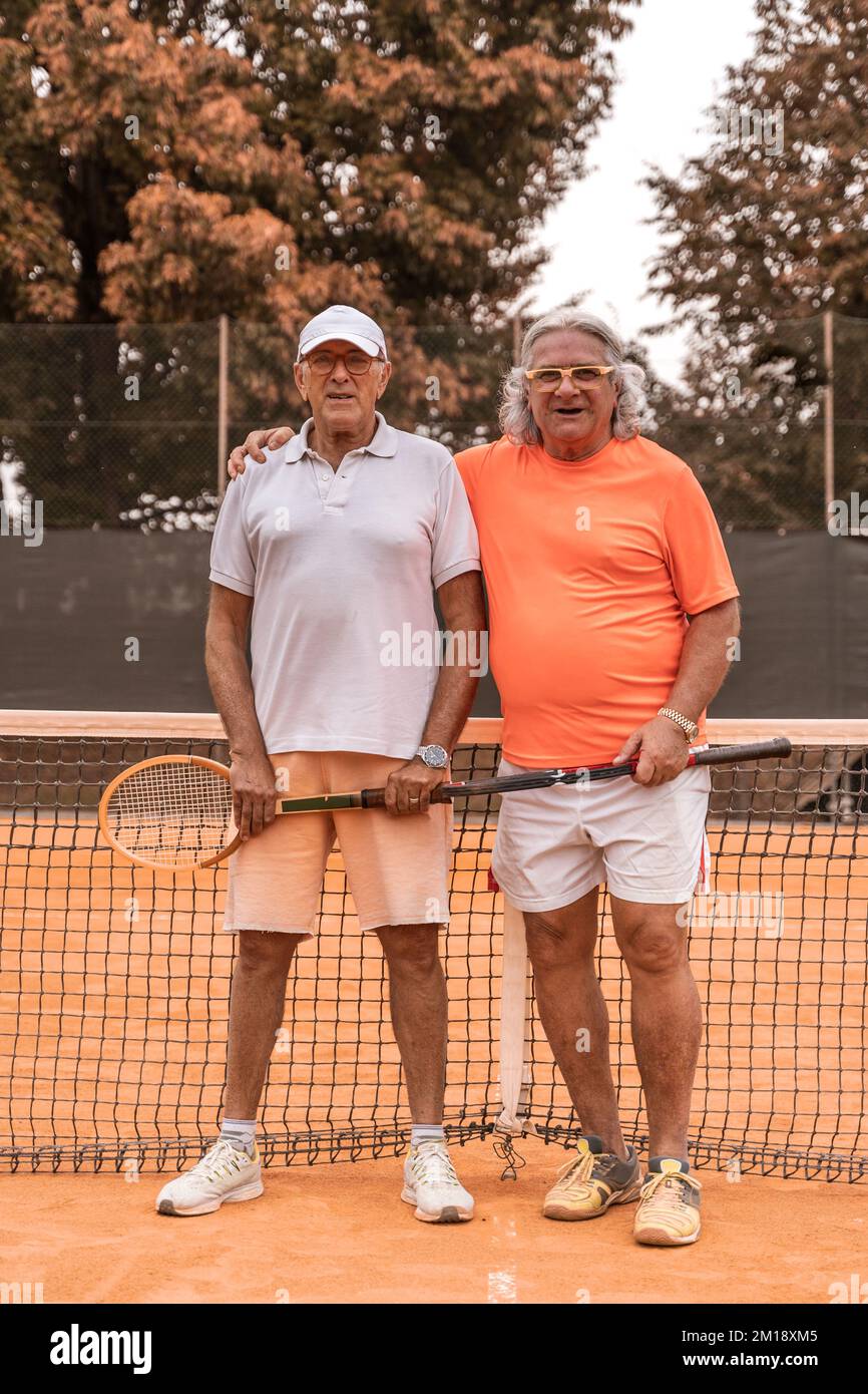 ritratto di due tennisti senior vestiti di abbigliamento sportivo che si  posano alla fine del gioco su un campo da tennis in terra battuta -  concetto di benessere ritirato Foto stock - Alamy