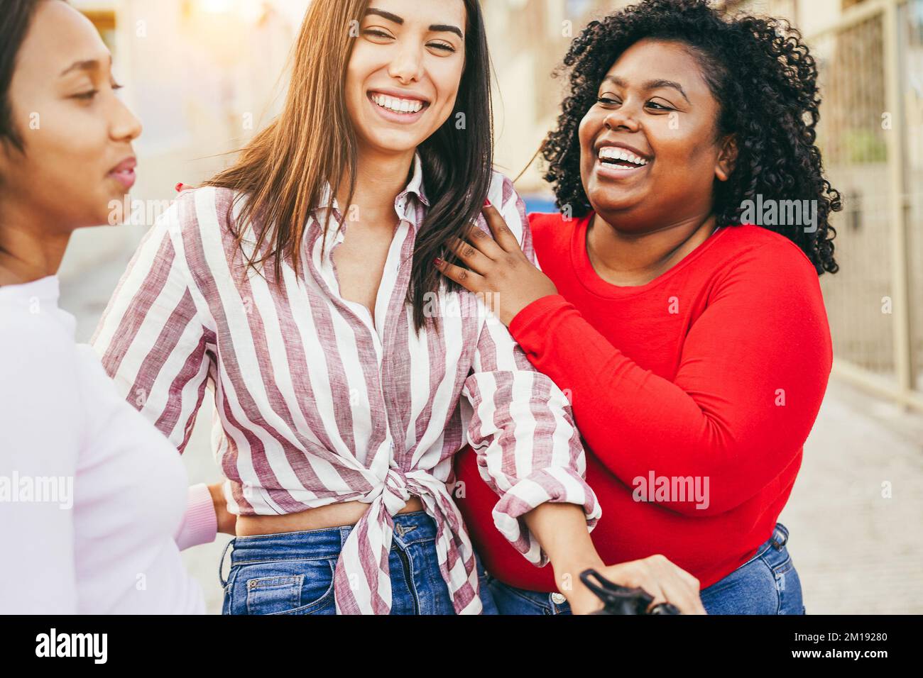 Ragazze multietniche felici che si divertono con scooter elettrico all'aperto - Focus sul viso ragazza centrale Foto Stock