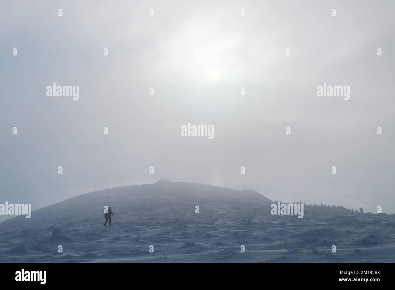 L'uomo cammina con uno zaino nella neve in un viaggio di trekking in montagna nel freddo inverno Foto Stock