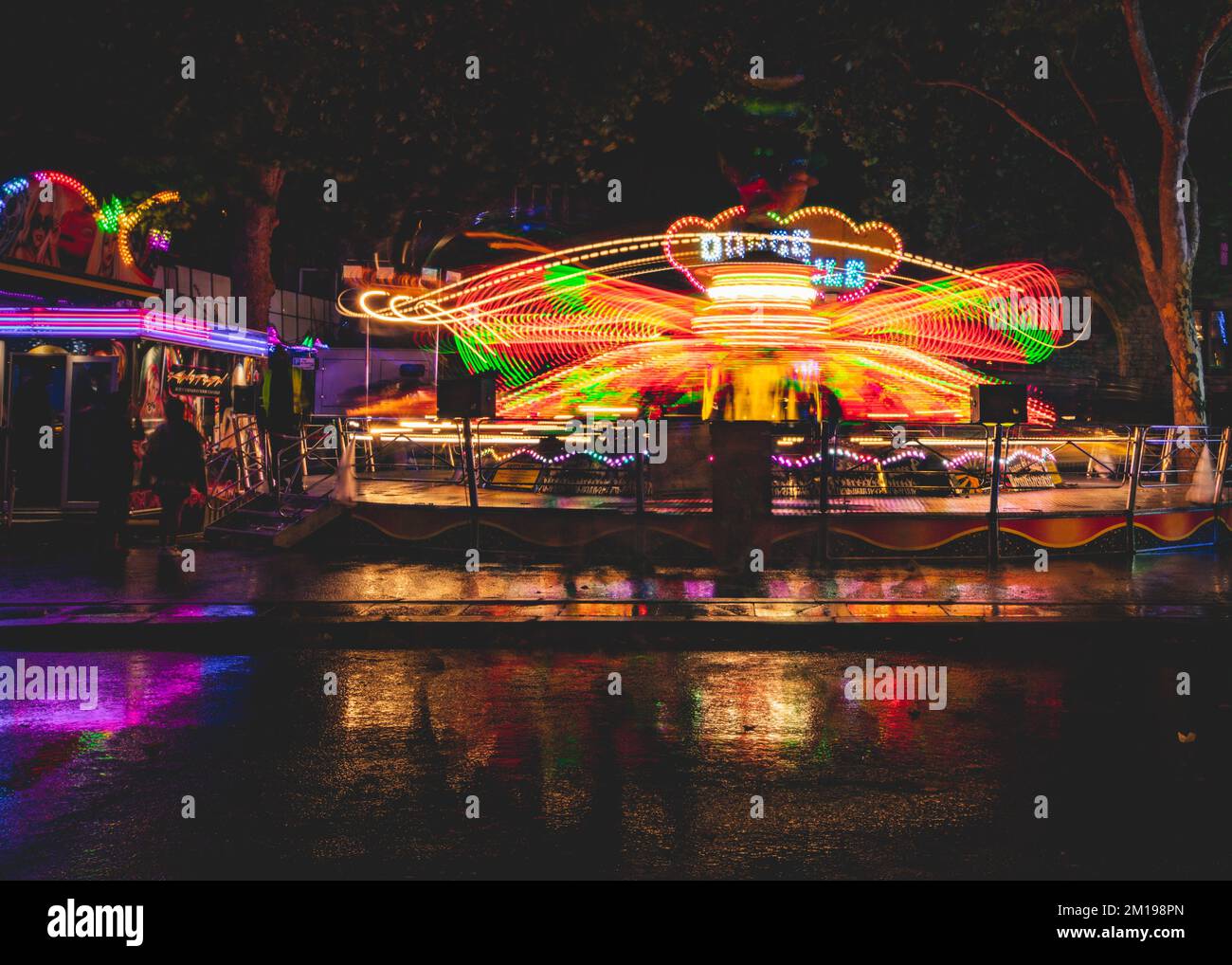 Una lunga esposizione di giostre illuminate alla fiera annuale di St Giles, Oxford Foto Stock