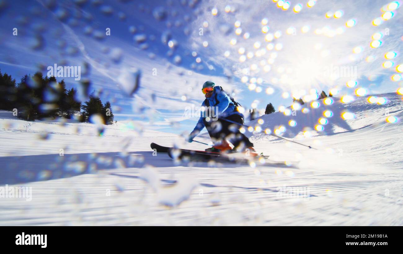 Sciatore professionista sulle piste delle alpi Svizzere e sciando la neve alla macchina fotografica. Gocce d'acqua visibili. Foto Stock