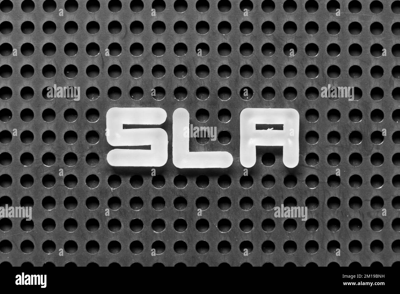 Lettera alfabetica bianca nella parola SLA (abbreviazione di Service Level Agreement) su sfondo nero di pegboard Foto Stock