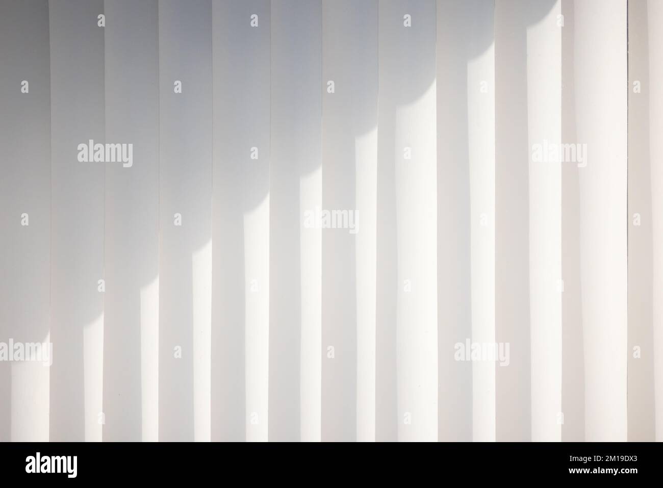 Tende bianche verticali standard sulla parete con motivo d'ombra, primo piano sfondo foto astratto Foto Stock
