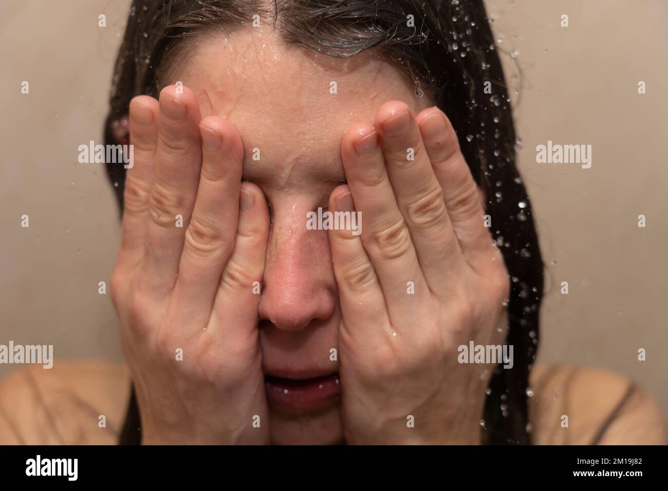 Giovane donna in doccia con la testa in mano. Concetto: Sensazione di depressione, vittima di prepotenza, disturbo bipolare, suicidio, burnout, sensazione di sfinito Foto Stock