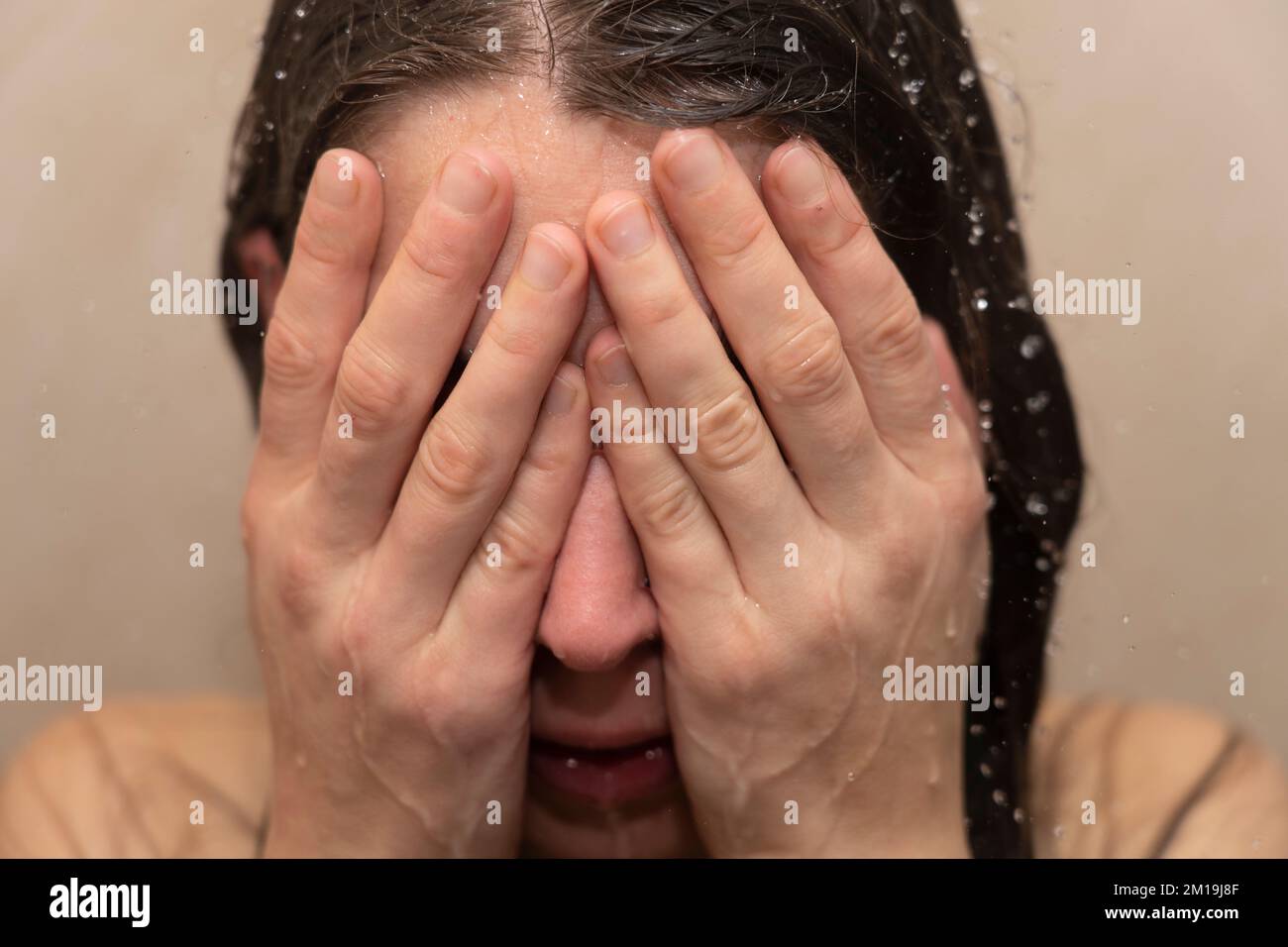 Giovane donna in doccia con la testa in mano. Concetto: Sensazione di depressione, vittima di prepotenza, disturbo bipolare, suicidio, burnout, sensazione di sfinito Foto Stock
