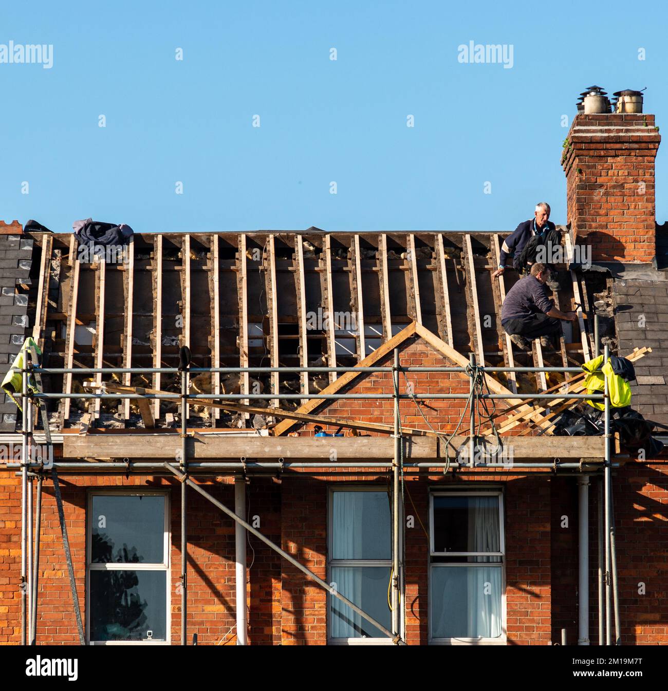 I costruttori di abbigliamento da lavoro installano nuovi attrezzi per tetti, attrezzi per tetti, trapano elettrico e li usano su nuovi tetti di legno con lamiere. Limerick, Irlanda, Foto Stock