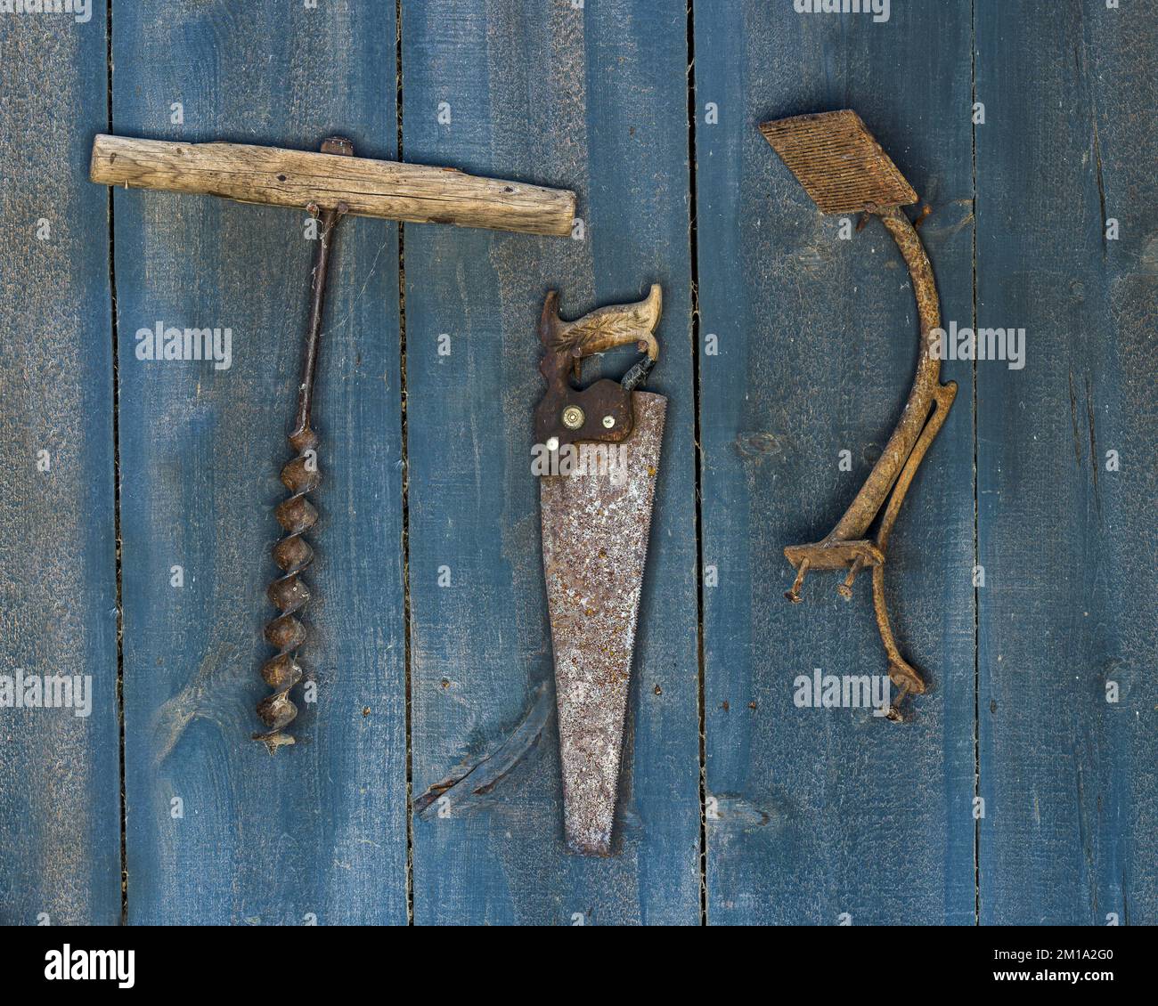 Tre attrezzi manuali primitivi appesi alla parete di legno blu di una bottega di fabbro a Midland, South Dakota Foto Stock