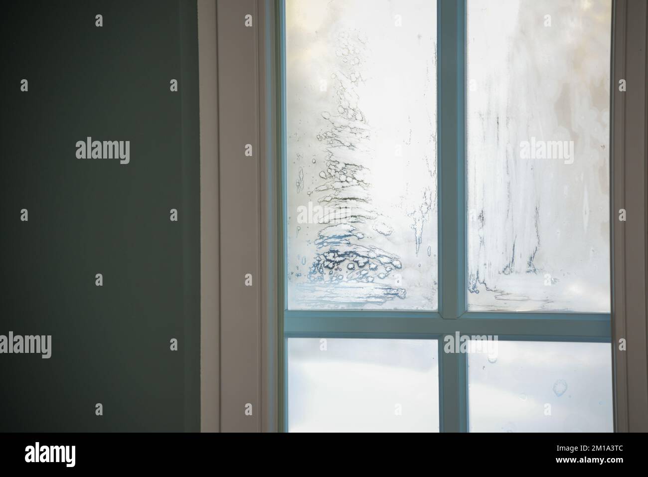 ghiaccio congelato su un vetro della finestra in una fredda giornata invernale. la luce del sole splende attraverso il vetro della stanza Foto Stock