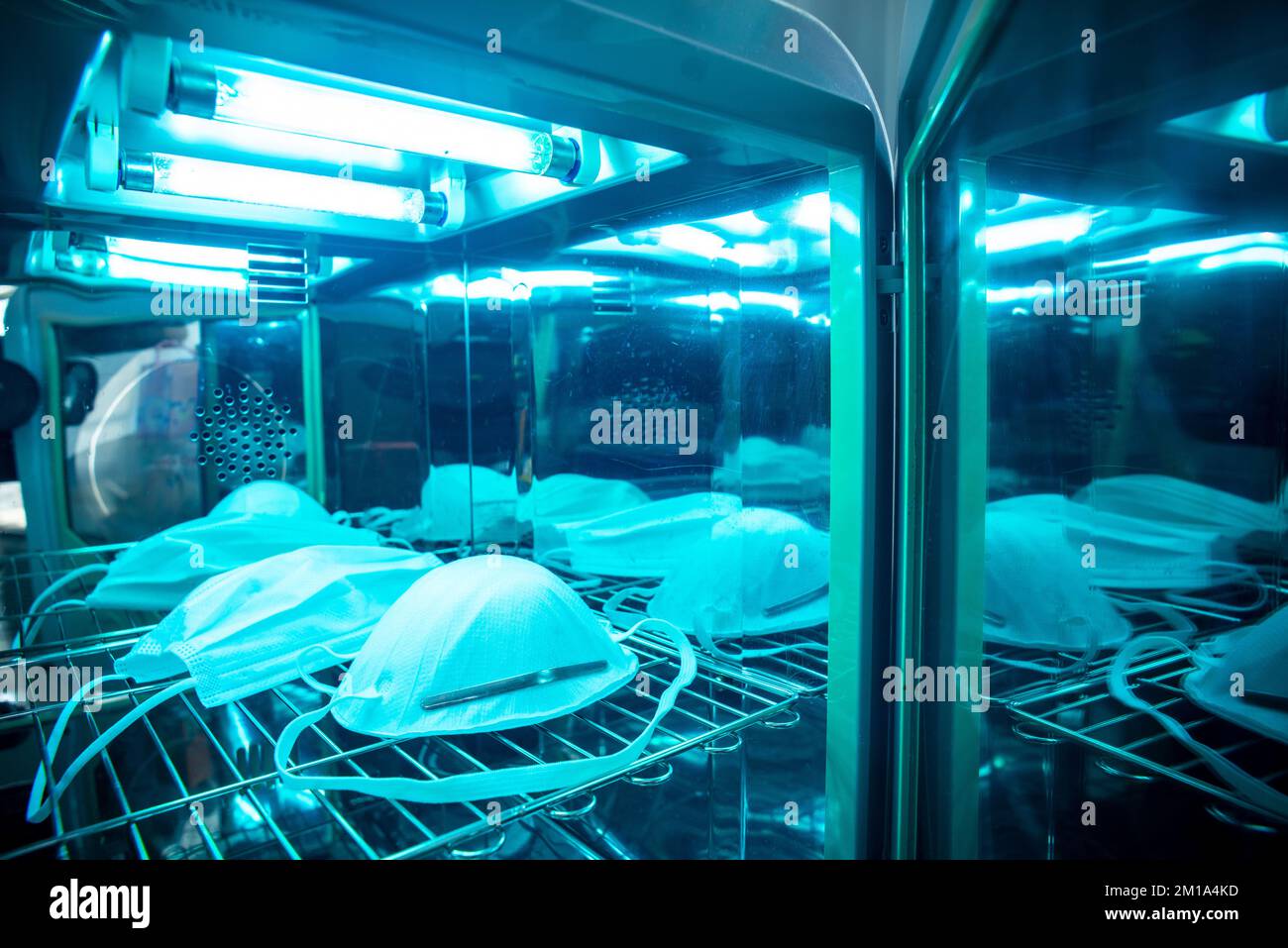 Sterilizzazione a raggi UV della maschera facciale per la disinfezione e il riutilizzo. Concetto di prevenzione COVID-19. Foto Stock