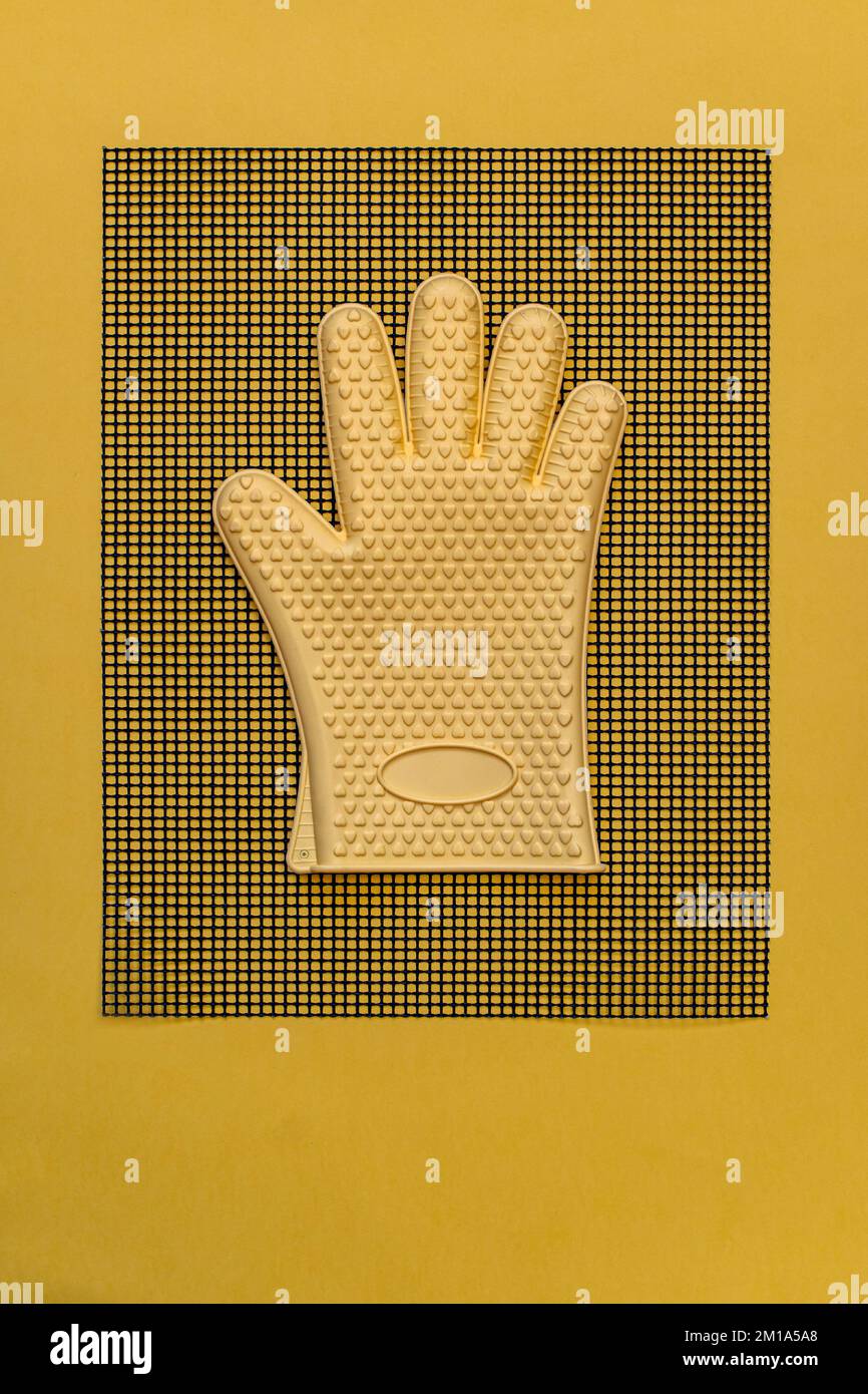 Guanto giallo resistente al calore su tappetino da cucina piatto Foto Stock