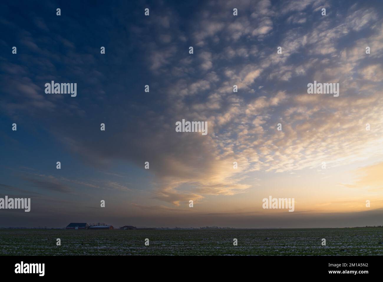 Una banda di nuvole sparse riempie il vasto cielo del tardo pomeriggio sulle pianeggianti terre della costa occidentale della Danimarca sul Mare di Wadden Foto Stock