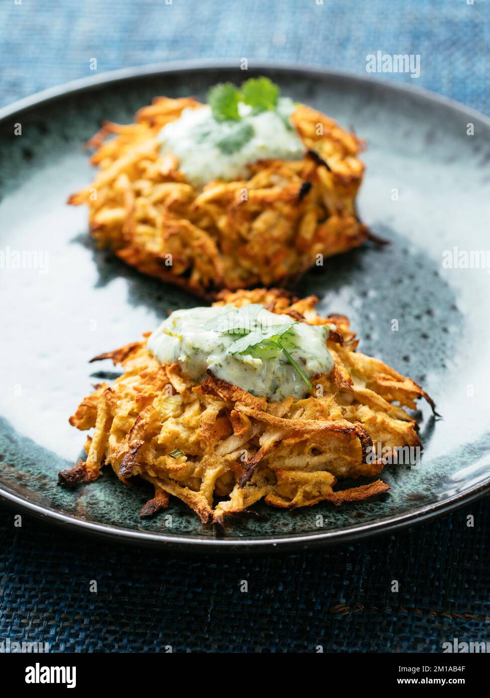 Pastinaca fatta in casa e frittelle di carote con salsa di coriandolo allo yogurt di soia. Foto Stock