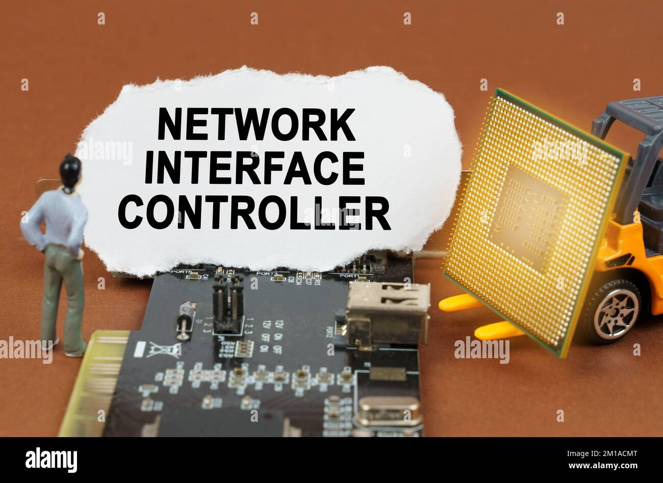 Concetto di computer. Sulla scheda con microcircuiti si trova una piastra di carta con l'iscrizione - Network Interface Controller. Nelle vicinanze si trova un caricatore di giocattoli con Foto Stock