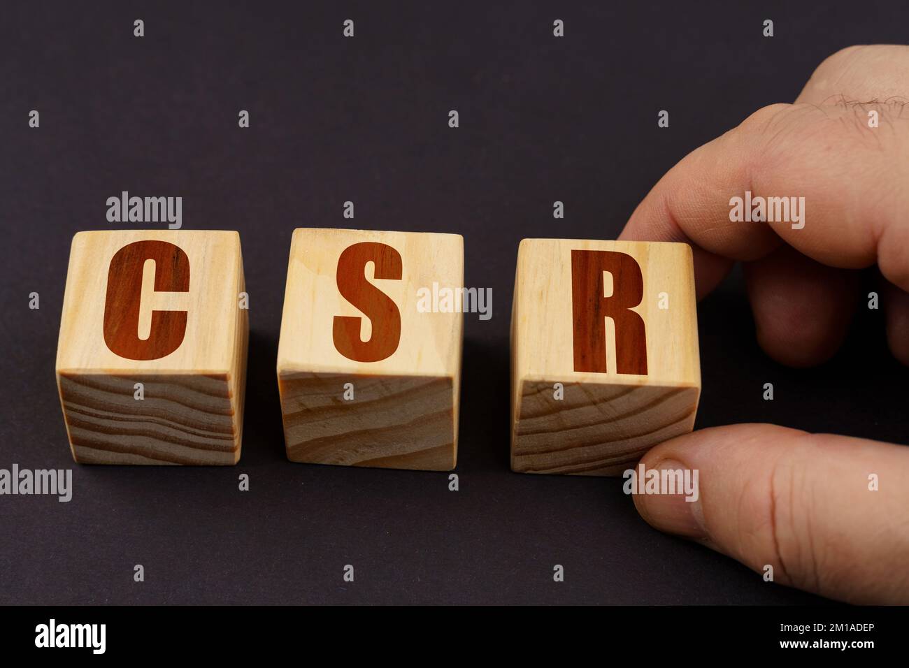 Concetto aziendale. Su una superficie nera, un uomo mette i cubi con l'iscrizione - CSR Foto Stock