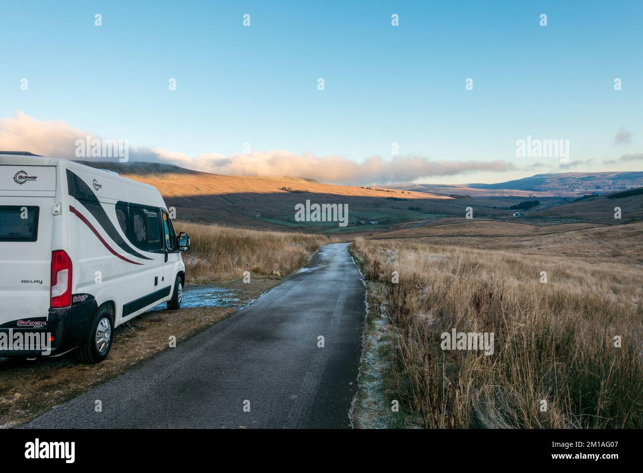 Panel van campervan parcheggiato su una tranquilla corsia di campagna a Wensleydale vicino Hawes in un inverno freddo mattina con gelo e ghiaccio sulla strada, Yorkshire UK Foto Stock