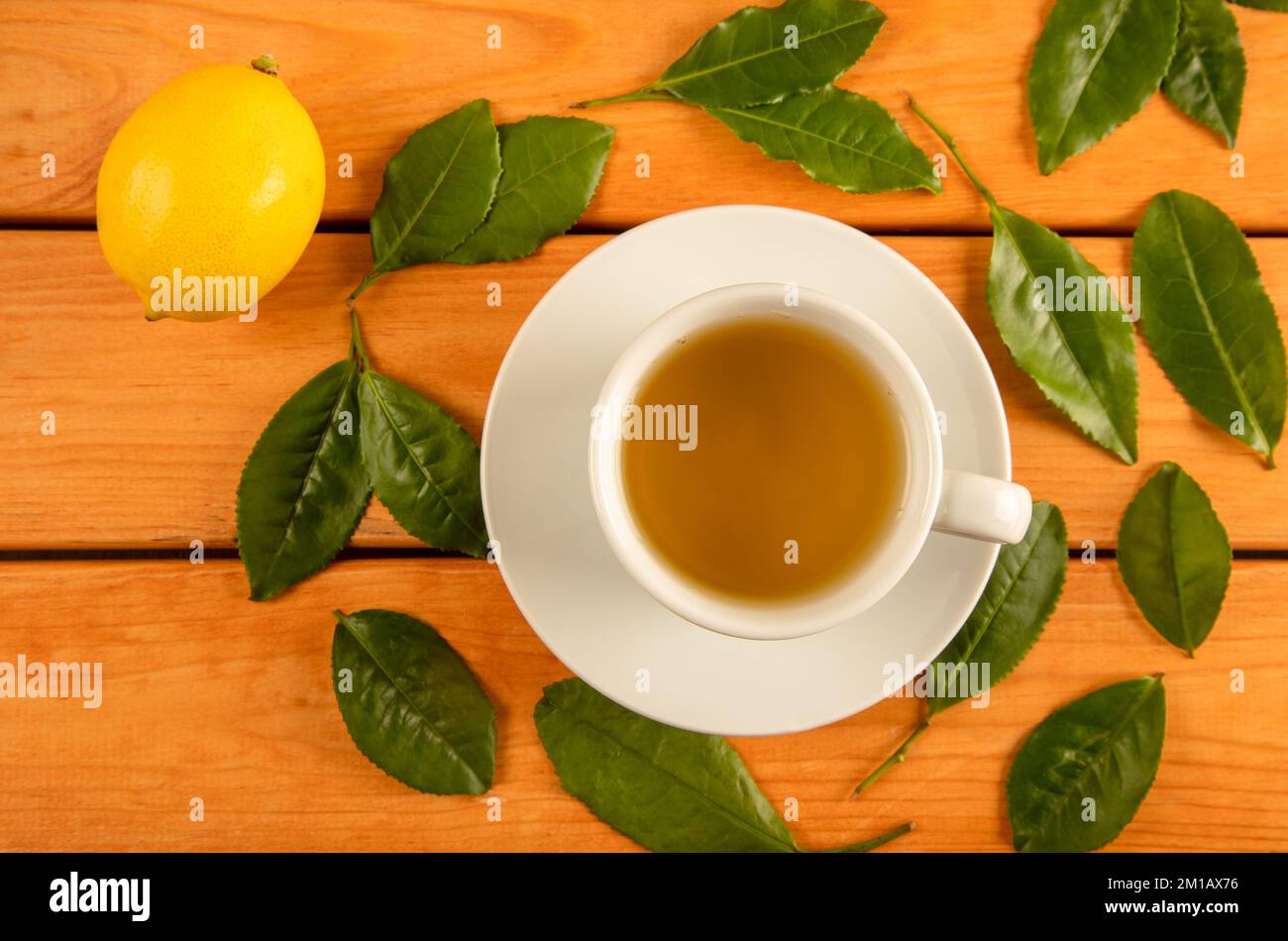 Una tazza di tè verde, foglie di tè e limoni Foto Stock