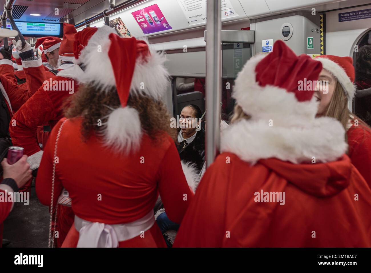 Un membro del pubblico reagisce all'invasione delle santas sul tubo a Londra. Foto Stock