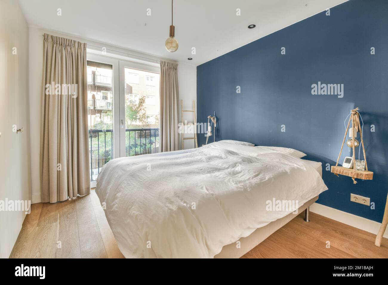 una camera da letto con pareti blu e letti bianchi nel mezzo della stanza, c'è un pavimento in legno Foto Stock