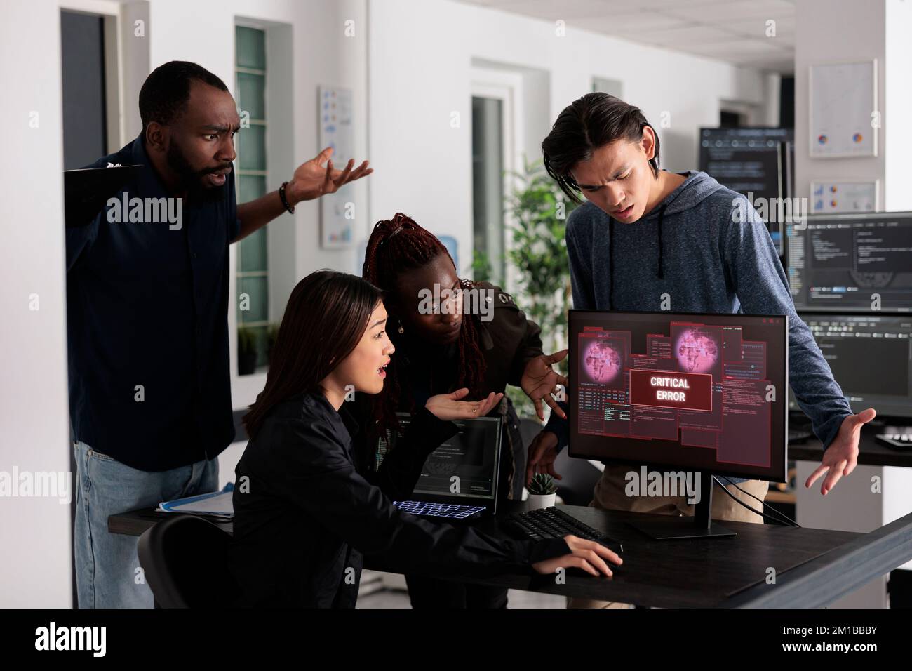 Team di programmatori IT che hanno violato il server Web, esaminando l'errore critico sul monitor del computer nell'ufficio dei big data. Diversi sviluppatori di software che cercano di risolvere il problema di hacking, firewall di sicurezza. Foto Stock