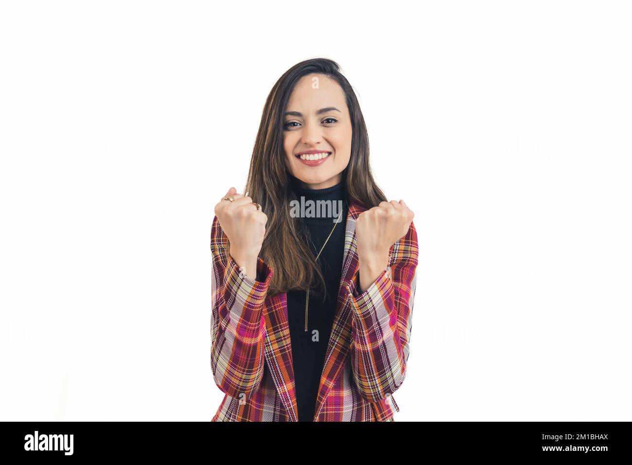 Giovane donna latino-americana che indossa abiti semi-formali guardando in macchina fotografica con ampio sorriso e sollevando entrambe le braccia in gesto di successo. Orizzontale sfondo bianco copia spazio ripresa studio. Foto di alta qualità Foto Stock