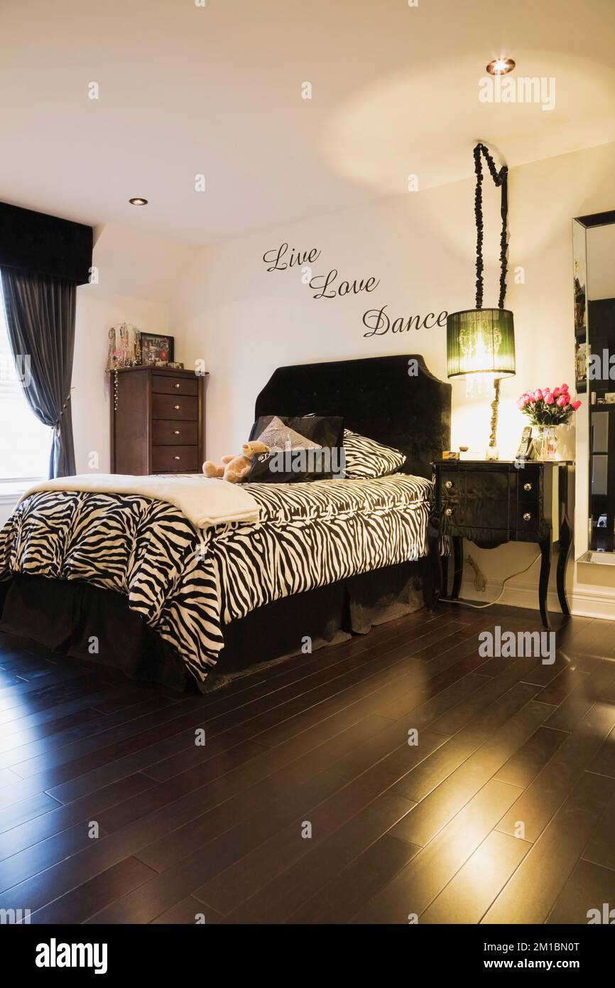 Letto singolo con motivi zebrati, copriletto e comodino nella camera da letto dei teenager all'interno di una casa lussuosa. Foto Stock
