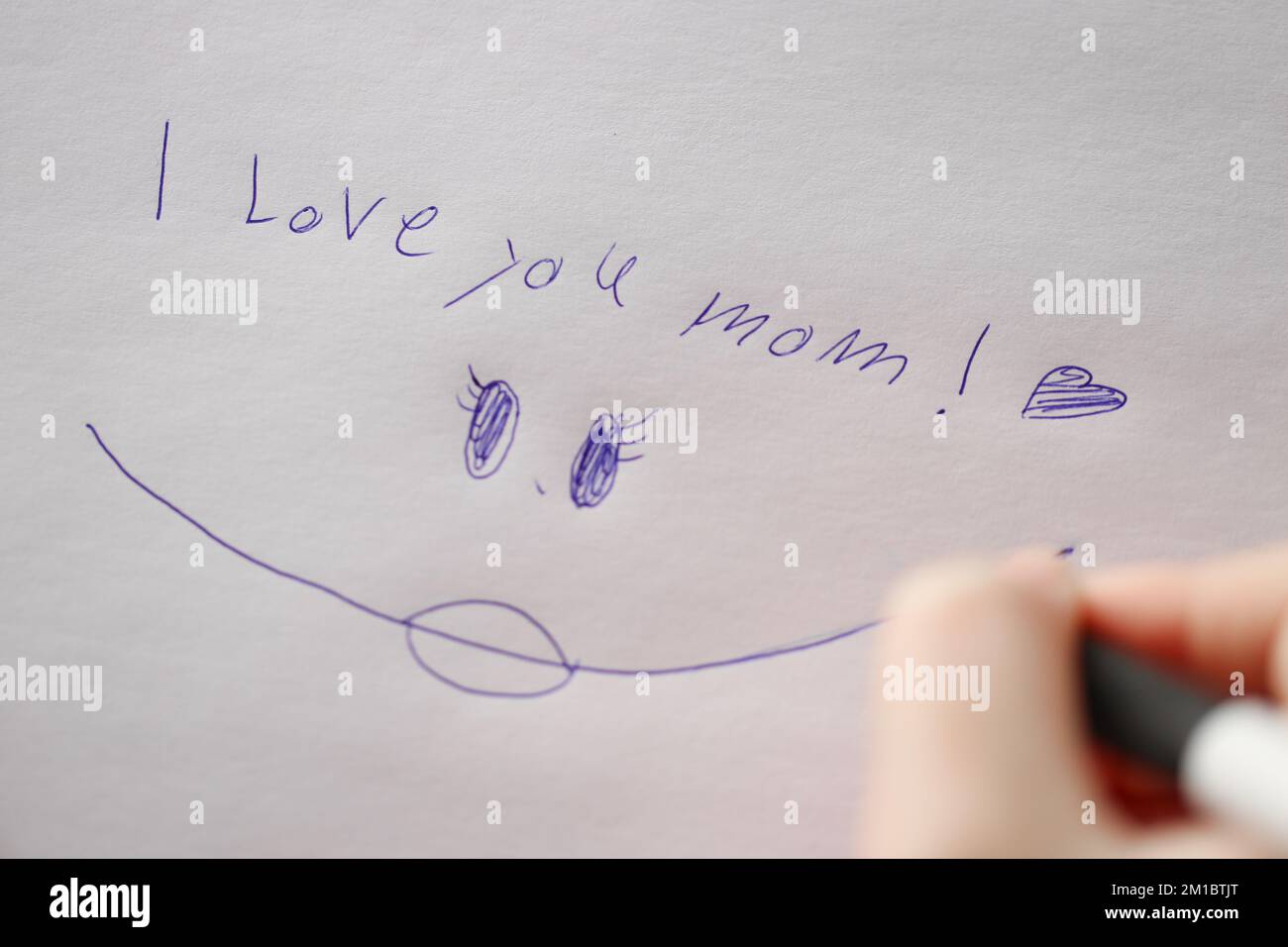 mamme giorno . Vi amo iscrizione mom su un foglio bianco e una mano di bambini con una pen.Holiday di tutte le madri Foto Stock