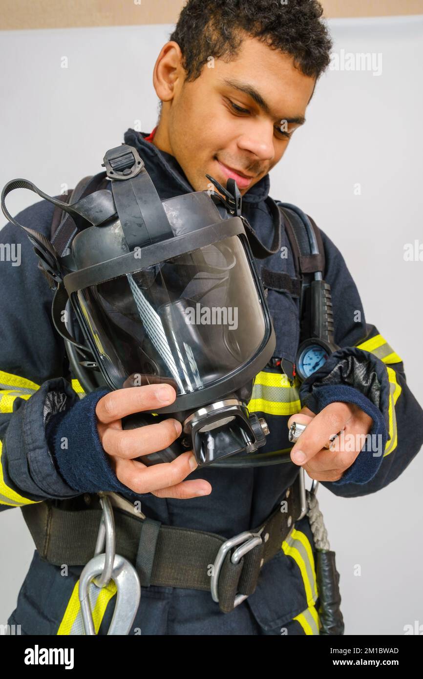 Maschera di respirazione protettiva completa in mano di pompiere non riconosciuto Foto Stock