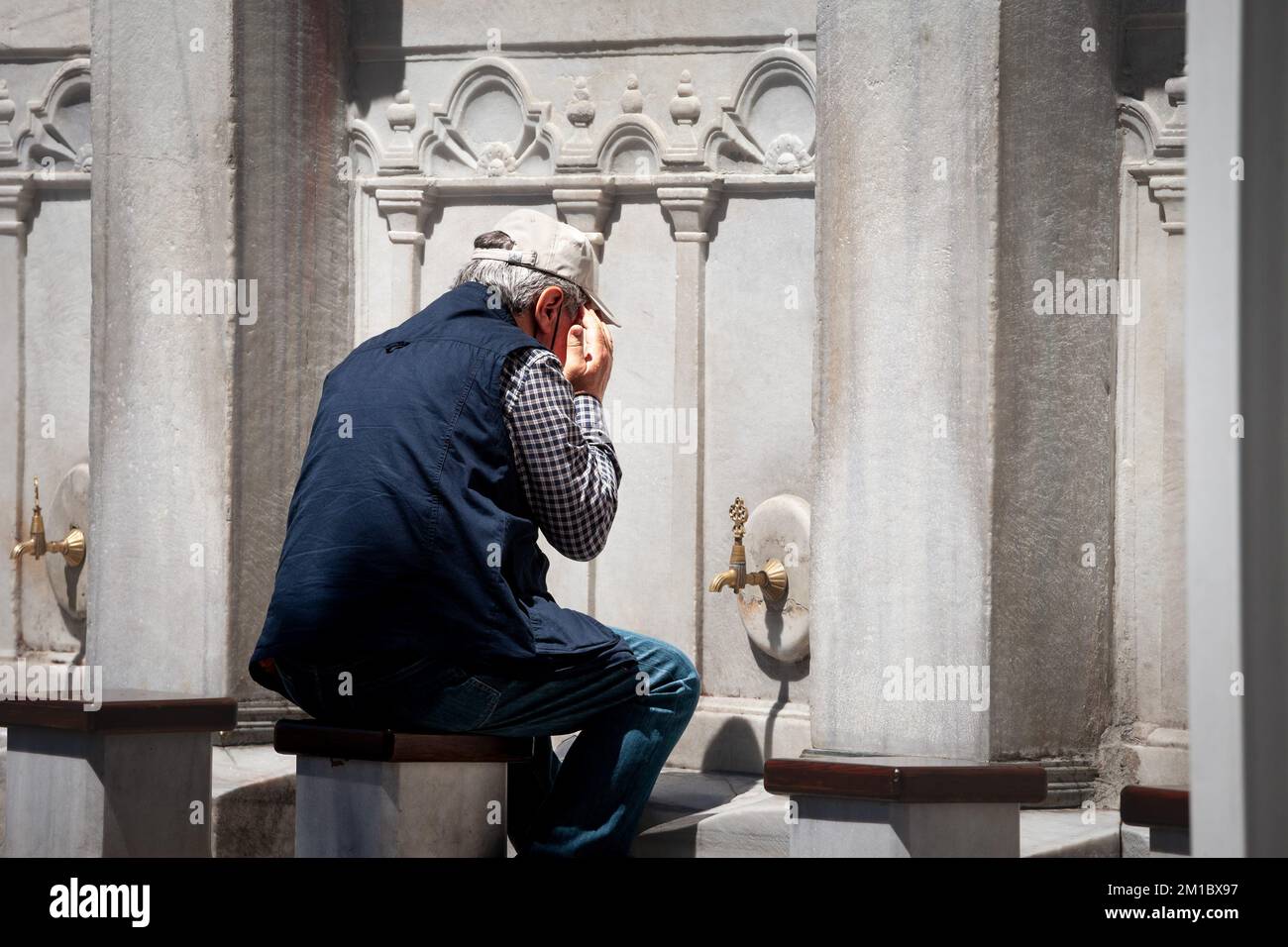 Immagine di un uomo che si lava il volto durante le abluzioni musulmane per prepararsi alla preghiera, di fronte ad una moschea, a istanbul, in turchia. Wudu è il p. Islamico Foto Stock