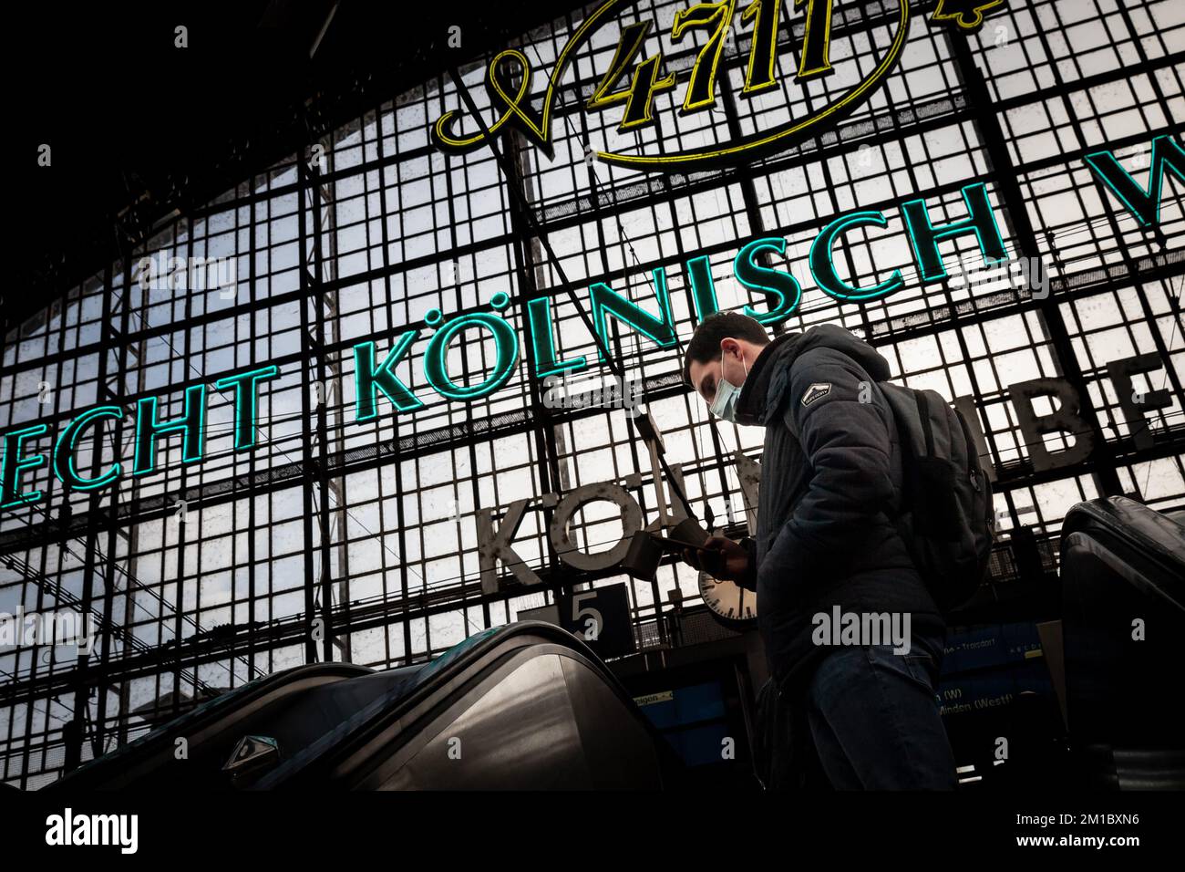 Immagine di un uomo in attesa di un treno sulle piattaforme della stazione ferroviaria di Colonia Koln hauptbahnhof, indossando maschere facciali durante il Coronavirus Covid 19 h. Foto Stock