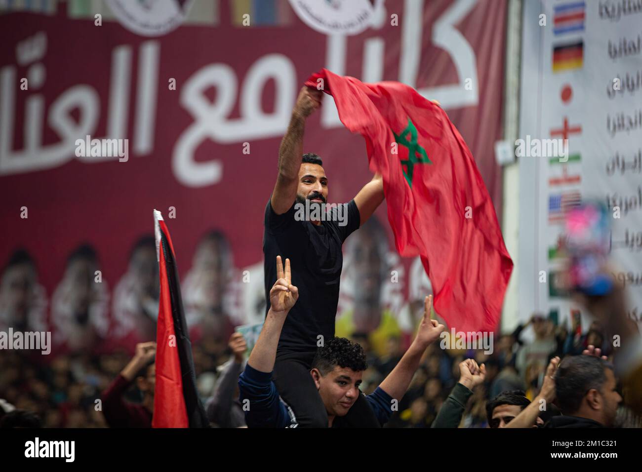 Gaza, Palestina. 10th Dec, 2022. Un palestinese sventola una bandiera marocchina mentre guarda la trasmissione in diretta della partita di finale della Coppa del mondo FIFA tra Marocco e Portogallo, che si è tenuta in Qatar, presso la Saad Sayel Sports Hall di Gaza. (Punteggio finale; Marocco 1-0 Portogallo) Credit: SOPA Images Limited/Alamy Live News Foto Stock