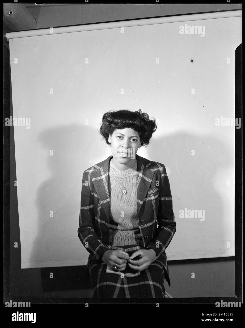 Una donna siede su uno sgabello, uno sfondo bianco dietro di lei,. Collezione Jack Miller Foto Stock