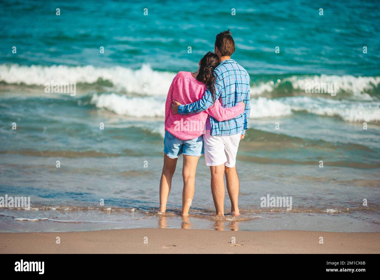 Giovane coppia innamorata della vacanza estiva in spiaggia. Uomo e donna felici guardano il mare Foto Stock